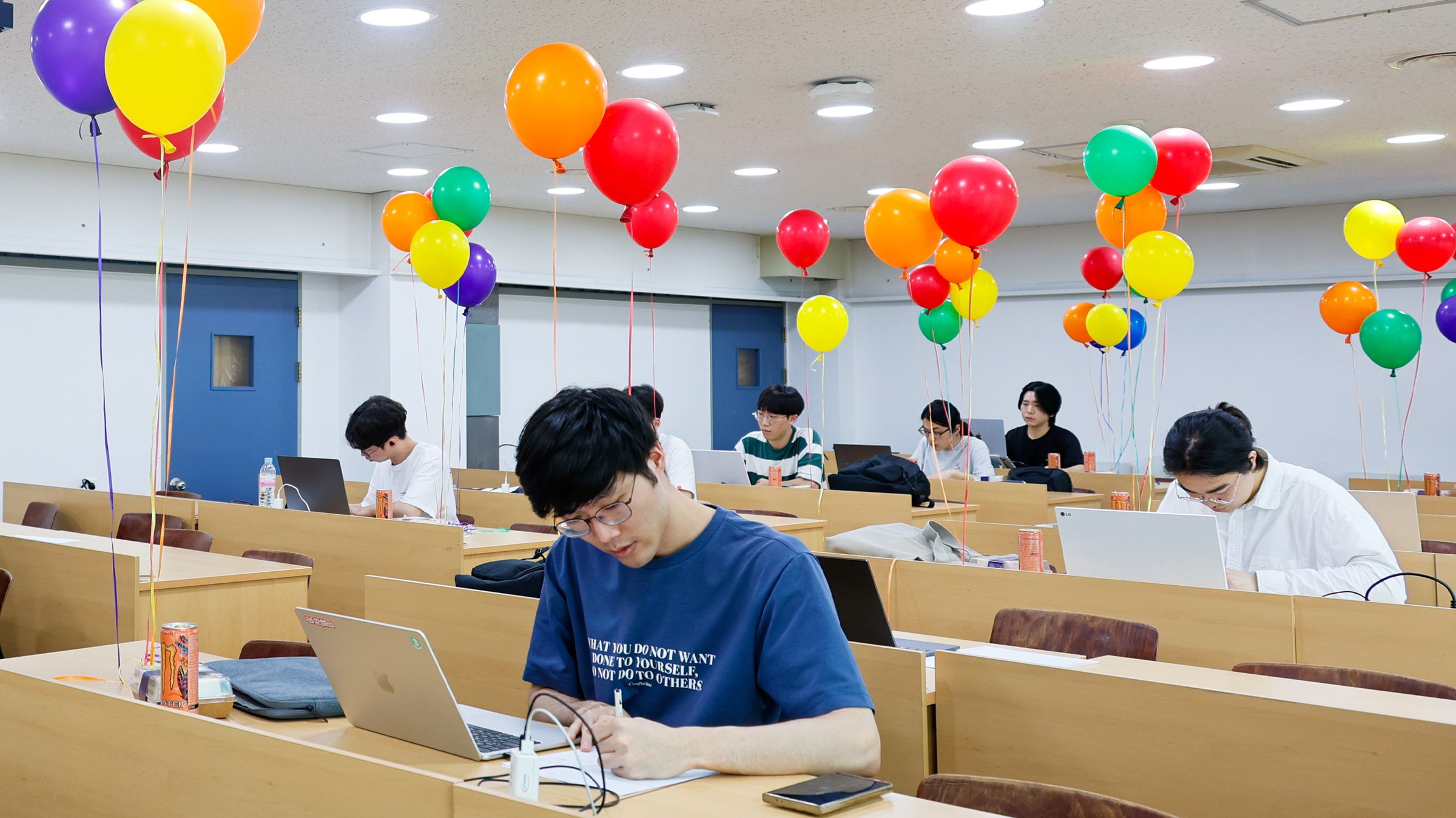 계단강의실에서 한 참가자가 노트북 옆에 종이를 펴 놓고 풀이를 적고 있다.